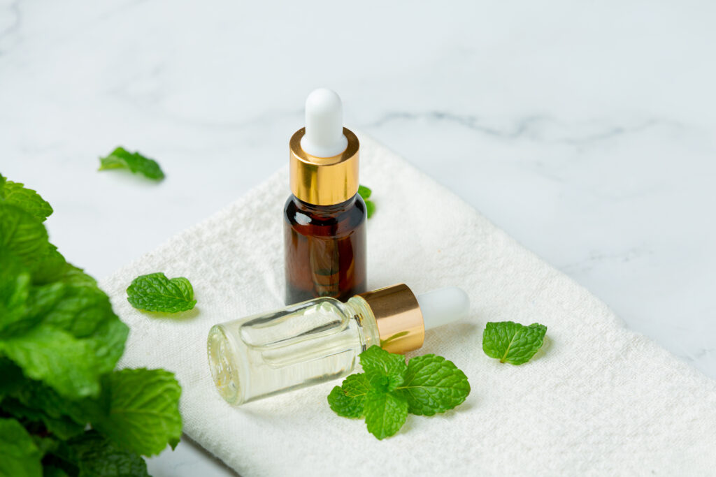 Essential oil of peppermint in bottle with fresh green peppermin